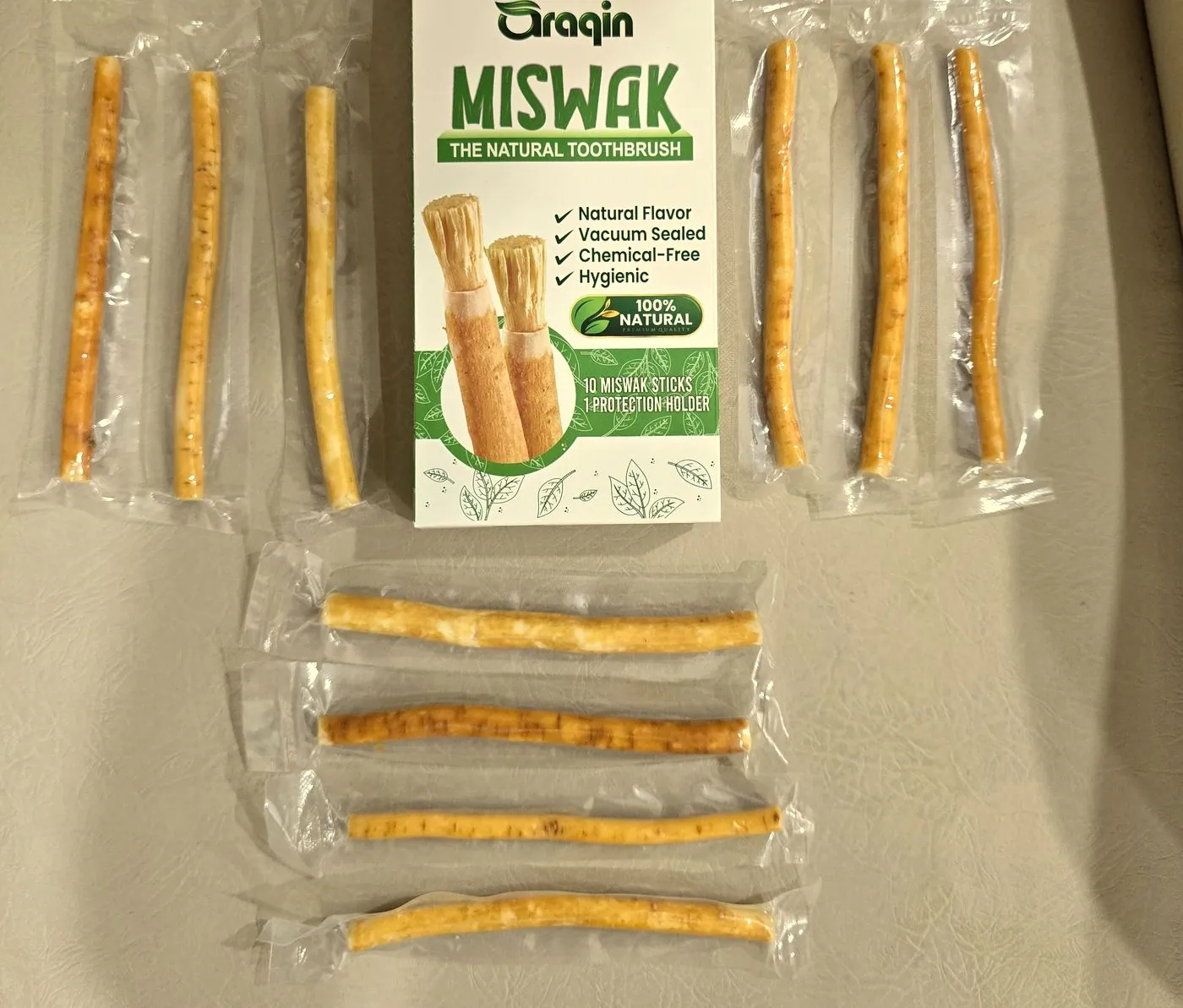 Ten individually sealed miswak sticks arranged around a deeper printed carton